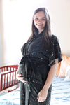 A mother and father smile while holding their newborn wrapped in a matching black paint-splatter swaddle. The mother wears a coordinating paint-splatter maternity robe, and the father wears a black “DAD” T-shirt included in the matching family hospital set. This paint splatter robe, dad shirt, and newborn swaddle bundle is ideal for maternity photos, labor and delivery outfits, hospital bag essentials, and baby announcement images.