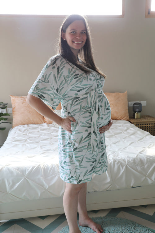 Woman wearing a green patterned dress standing in a bedroom.
