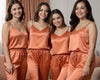Bridesmaid satin pajama set in burnt orange featuring four women wearing matching personalized camisole tops and drawstring pants, perfect for bridal party getting-ready outfits, bachelorette gifts, and wedding morning photos.